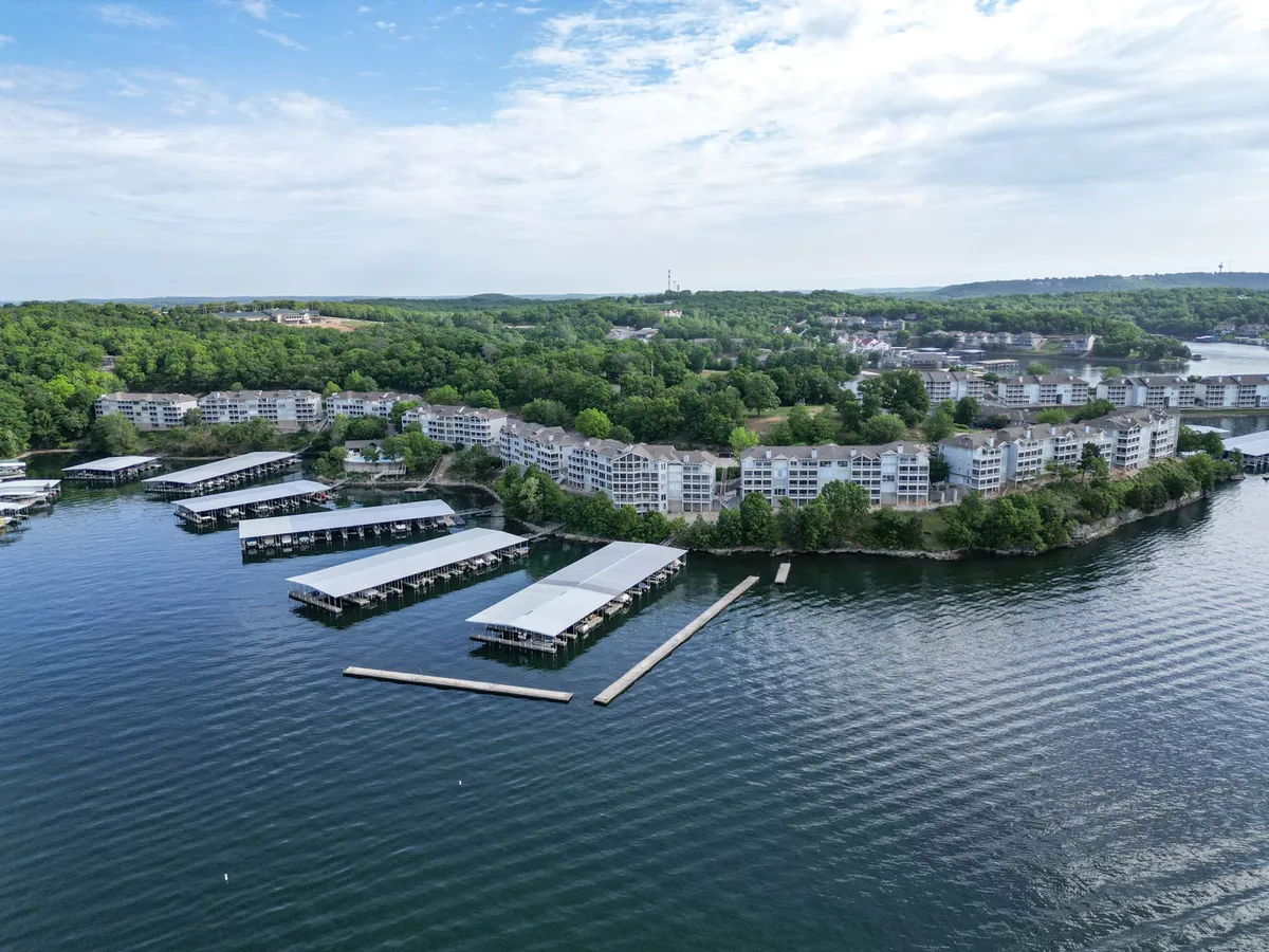 A scenic lakeside scene featuring the lake, marina, residential buildings, and surrounding greenery. The sun sets over the water, creating a relaxed yet lively atmosphere for gatherings, boating, and lakeside strolls.