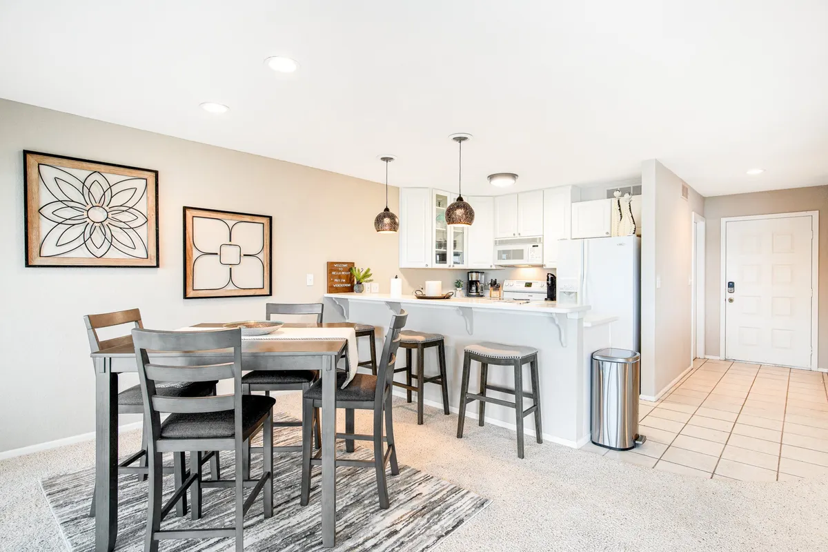 A cozy dining table set close to the kitchen counter, complemented by decorative wall art. The arrangement suggests a space perfect for family meals, social gatherings, or casual brunches.