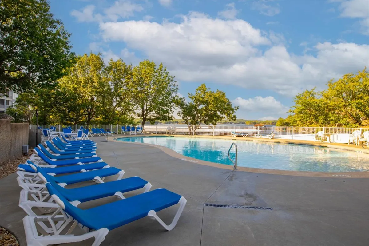 A serene swimming pool area surrounded by lounge chairs and trees. The tranquil setting invites residents to take a refreshing swim, sunbathe, or socialize after a productive day. The pool is a key resort amenity for relaxation and unwinding.