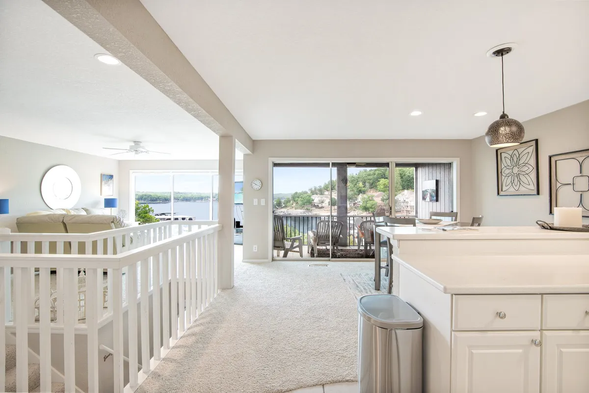 An open-plan space featuring a large kitchen island, adjacent dining area, and expansive windows that let in natural light. The scene is arranged for gatherings, with comfortable seating and a clear view that invites family and friends to linger.