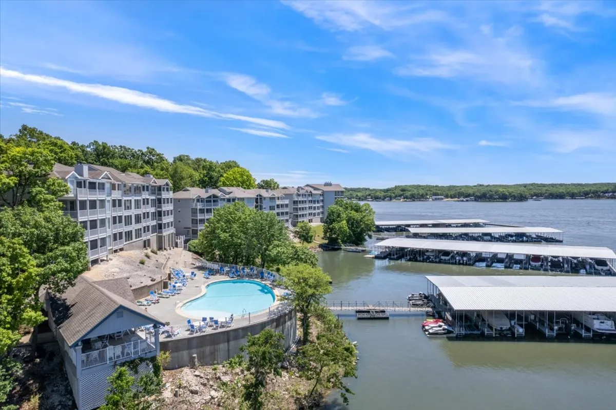 An expansive swimming pool sits beside a marina and dock, all set against a backdrop of lush greenery. Residents are enjoying the pool and the boating facilities, highlighting both water recreation and opportunities for social interaction.